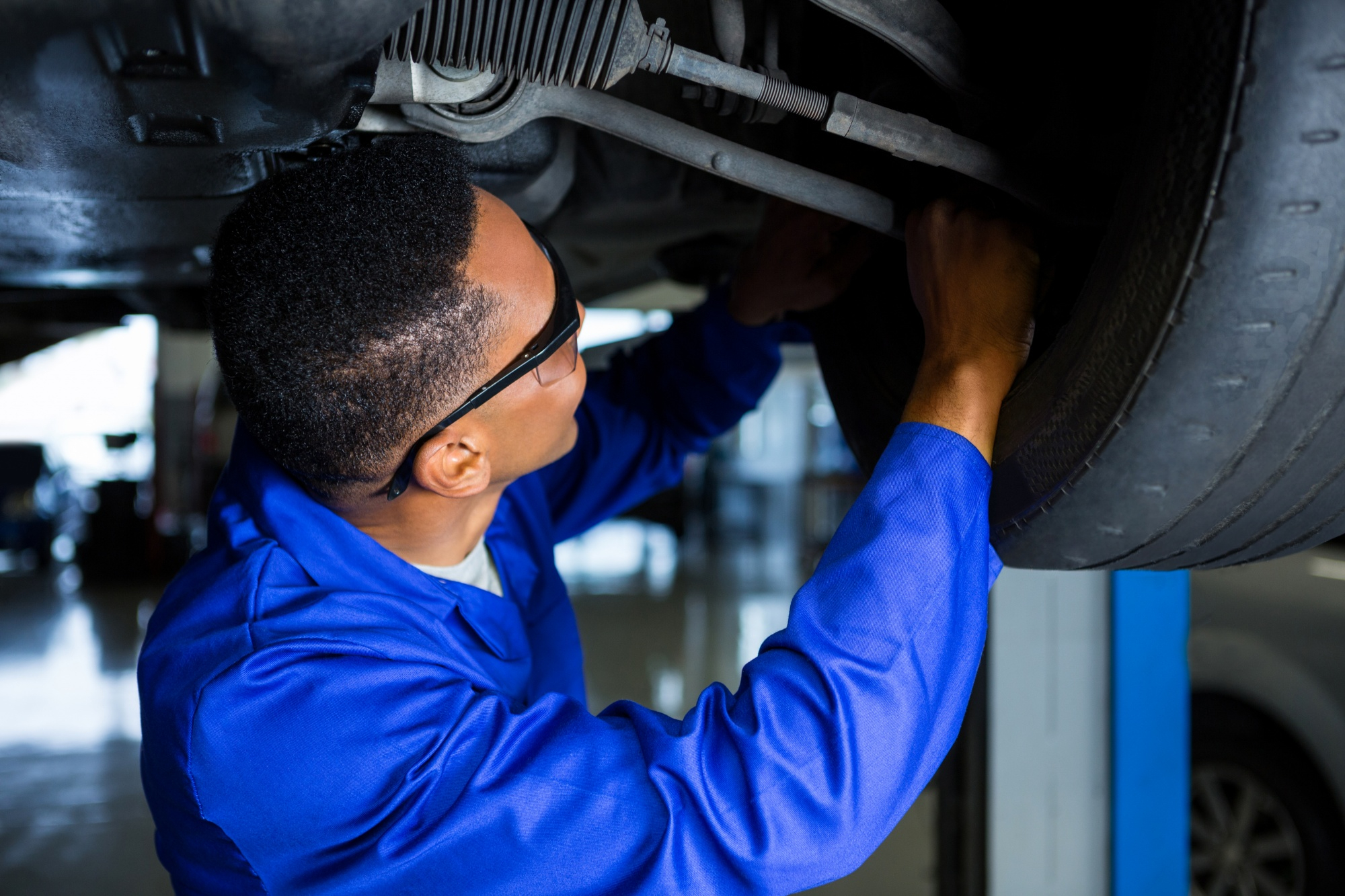 Mechanic inspecting undercarriage of car